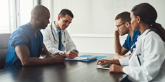 Physician executives gathered around a table in a conference room