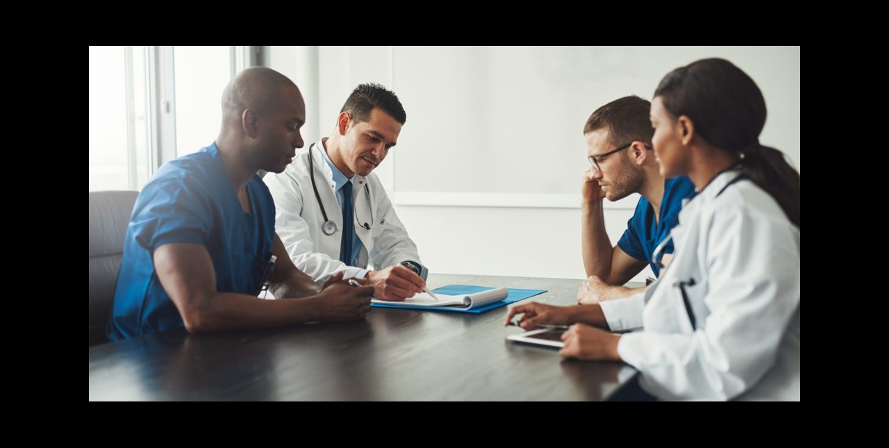 Physician executives gathered around a table in a conference room