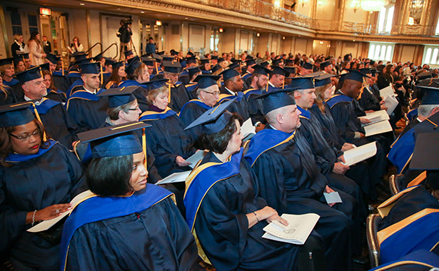 Group of individuals seated with caps and gowns at Fellow induction ceremony